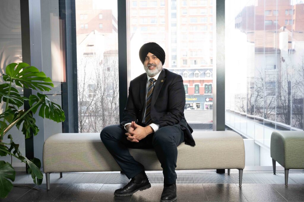 Man in business attire sitting on a bench in a modern office with city view.